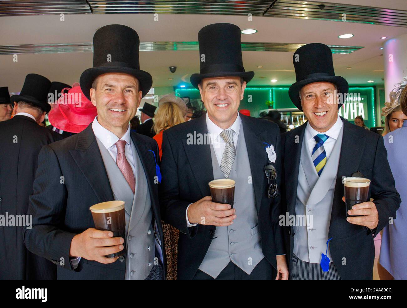 Tre uomini in Top Hats and Tails con tre pinte di Guiness il giorno Derby all'ippodromo di Epsom. Il Derby è una delle gare pianeggianti Classic. Foto Stock