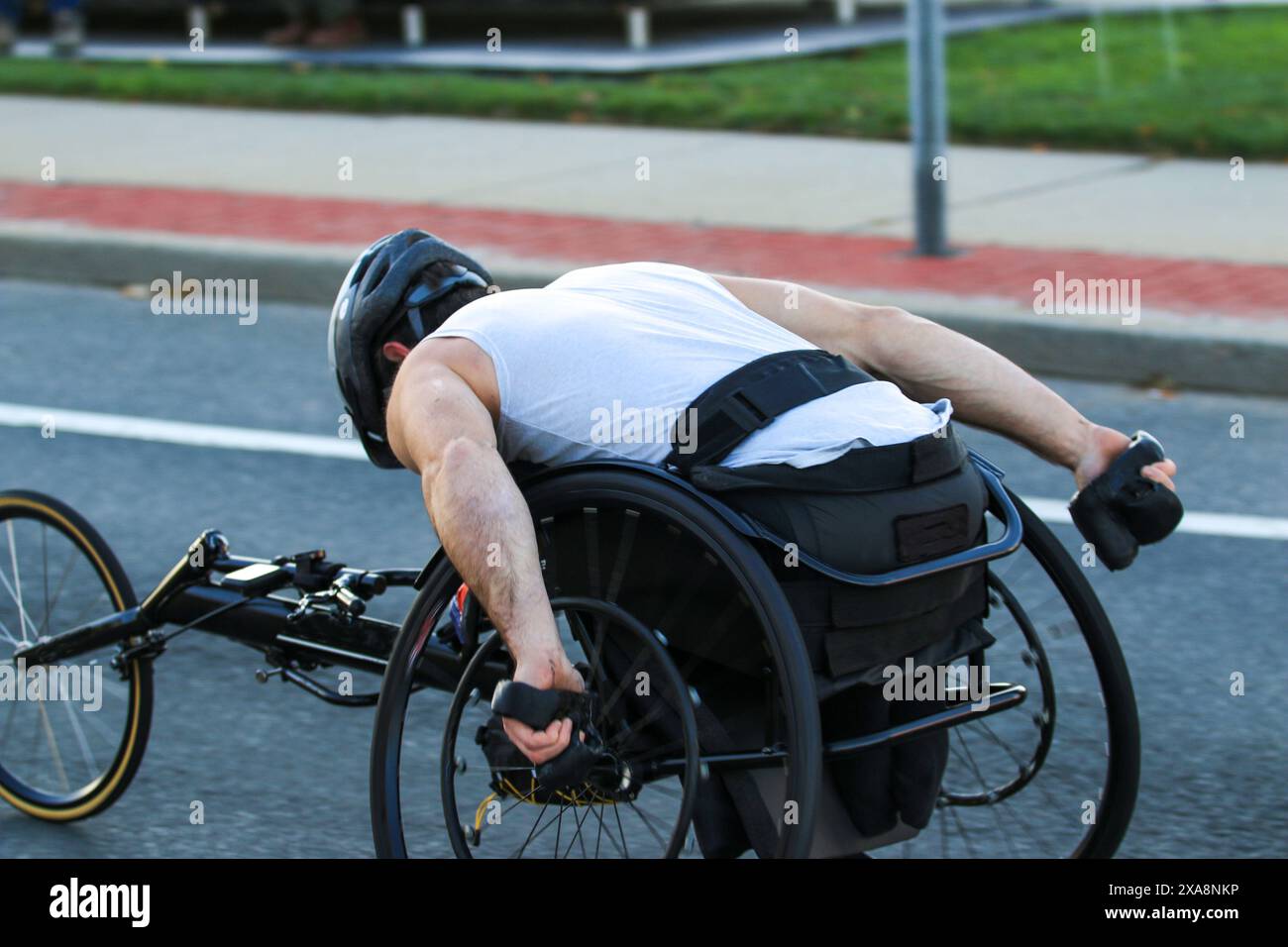 Primo piano di una vista laterale di un uomo che gareggia su una sedia a rotelle durante una maratona. Foto Stock