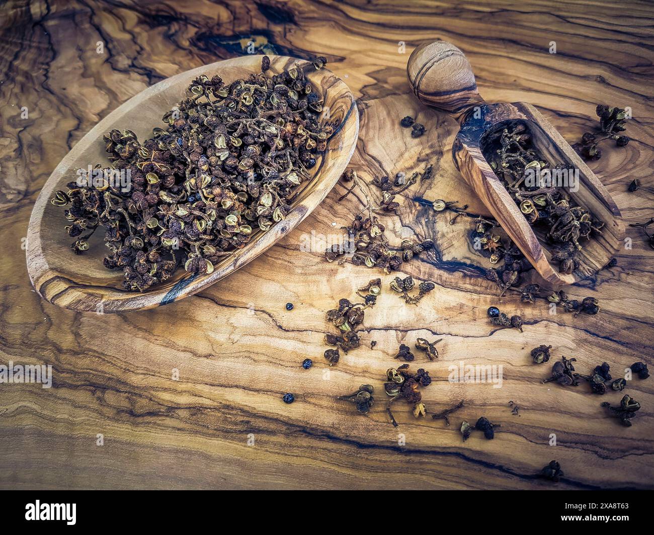 Andalimano (Zanthoxylum acanthopodium), pepe andalimano in una ciotola di legno e su sessole di legno Foto Stock