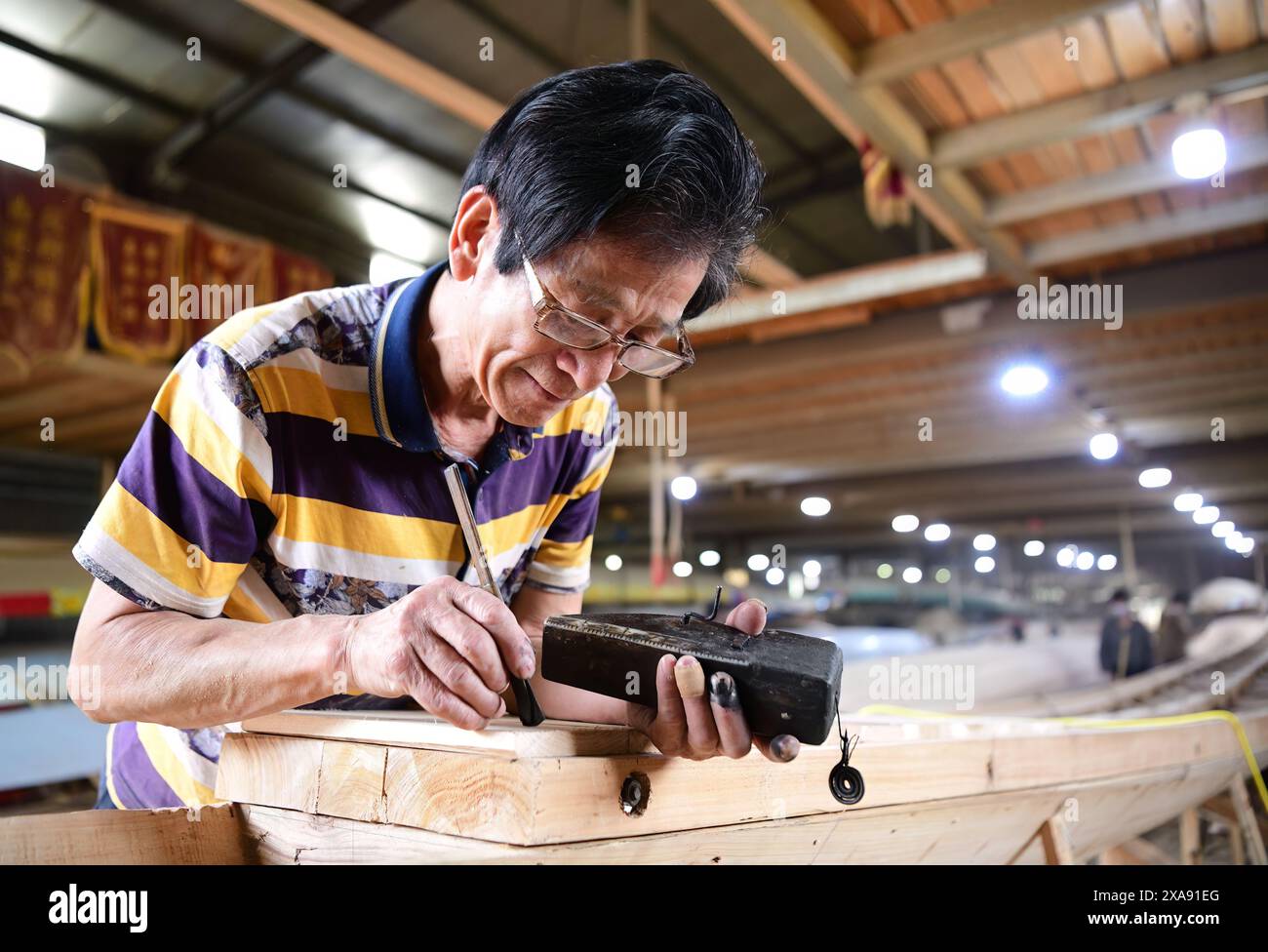 (240605) -- FUZHOU, 5 giugno 2024 (Xinhua) -- Un lavoratore usa un pennarello per tracciare linee rette per una barca drago in una fabbrica di dragoni nel villaggio di Fangzhuang, Fuzhou, nella provincia del Fujian, nella Cina sud-orientale, 3 giugno 2024. Con l'avvicinarsi del Dragon Boat Festival, i lavoratori del villaggio di Fangzhuang stanno lavorando per servire le barche drago sia dall'interno che dall'estero. Soprannominata "il villaggio della barca del Drago", Fangzhuang ha una storia di drago-barca da oltre 700 anni. Ogni anno, oltre 200 barche vengono vendute da qui al mondo. Fang Shaohuang, erede del drago di Fangzhuang bo Foto Stock
