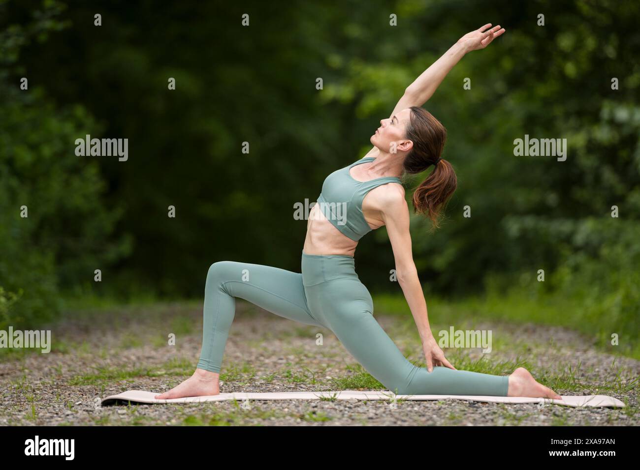 Donna sportiva che fa yoga nel parco, esercizio di stretching, affondo basso. Foto Stock