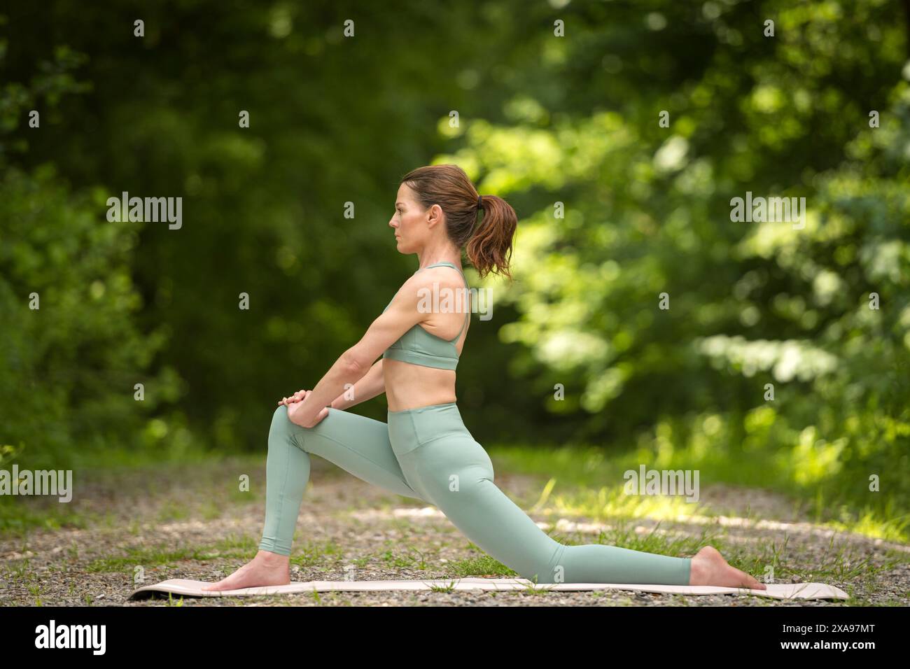 Donna sportiva che fa yoga nel parco, esercizio di stretching, affondo basso. Foto Stock