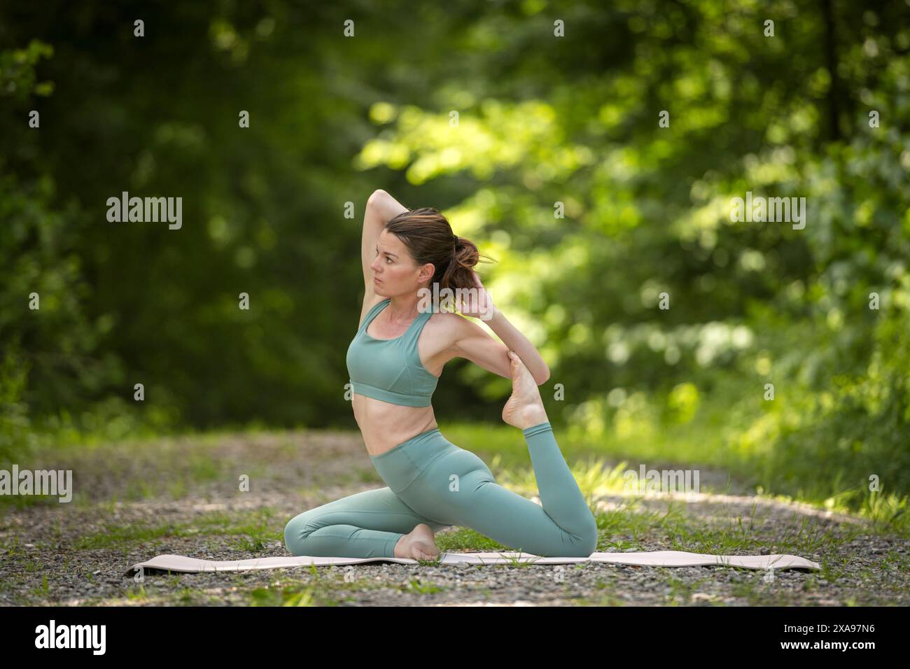 Donna sportiva che pratica yoga nel parco, posa sirena. Foto Stock