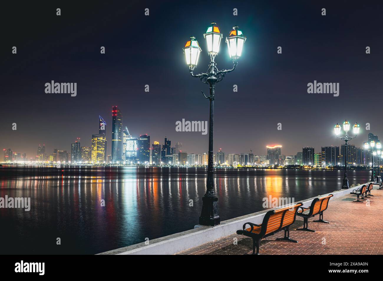 Skyline urbano con grattacieli di notte. Paesaggio urbano illuminato di Abu Dhabi, Emirati Arabi Uniti. Foto Stock