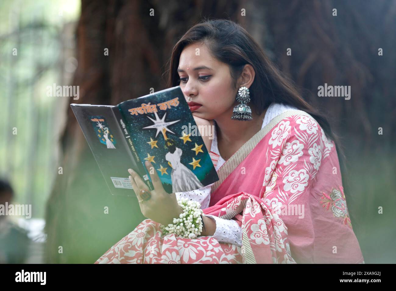 Dacca, Bangladesh - 23 maggio 2024: Uno studente che legge un libro seduto in una biblioteca aperta nella zona dell'Università di Dacca, Dacca, Bangladesh. Foto Stock