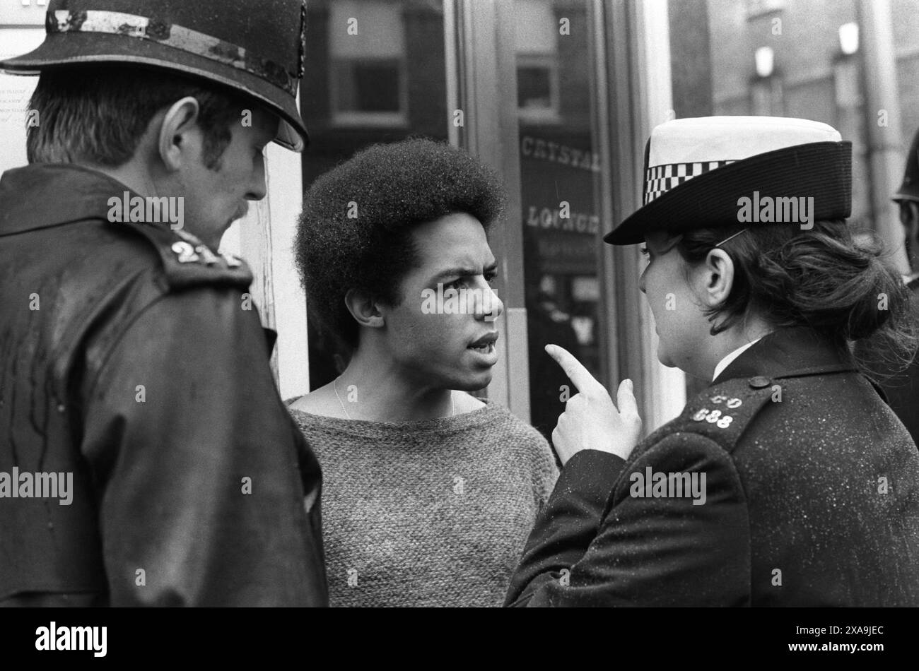 Legge SUS, ha permesso alla polizia di fermarsi e cercare qualsiasi "persona sospettata" in qualsiasi momento. La poliziotta del gruppo speciale di pattuglia dà un dito a un giovane nero. Kings Road, Chelsea, Londra, Inghilterra 1977. 1970 UK HOMER SYKES Foto Stock Legge SUS, ha permesso alla polizia di fermarsi e cercare qualsiasi "persona sospettata" in qualsiasi momento. La poliziotta del gruppo speciale di pattuglia dà un dito a un giovane nero. Kings Road, Chelsea, Londra, Inghilterra 1977. 1970 UK HOMER SYKES Foto Stock