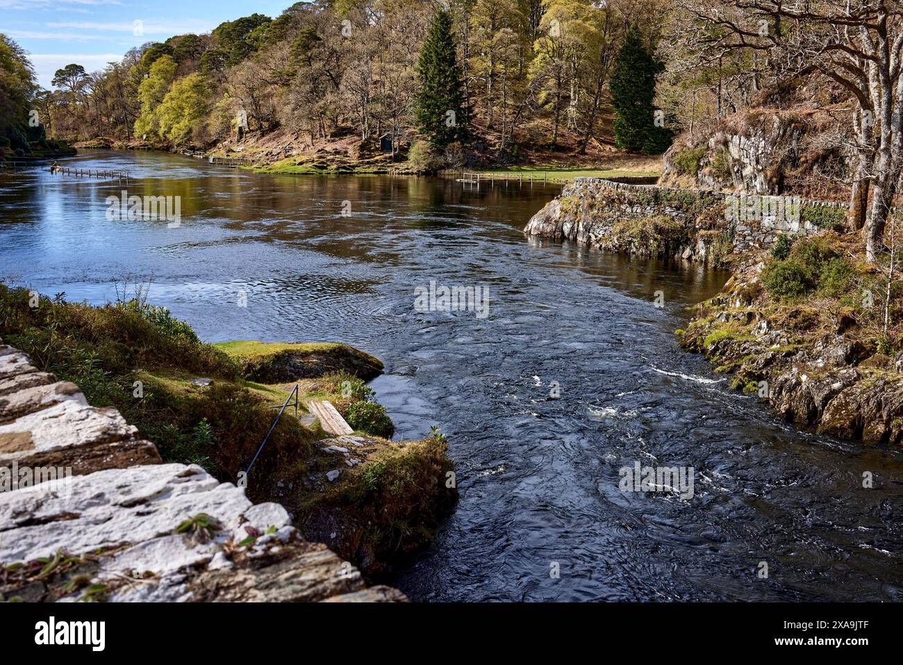 Forzato attraverso lo stretto ponte, con acqua turbolenta, una vista del fiume Shiel a sud dal fiume Shiel Old Bridge con bancarelle di pesca vuote Foto Stock