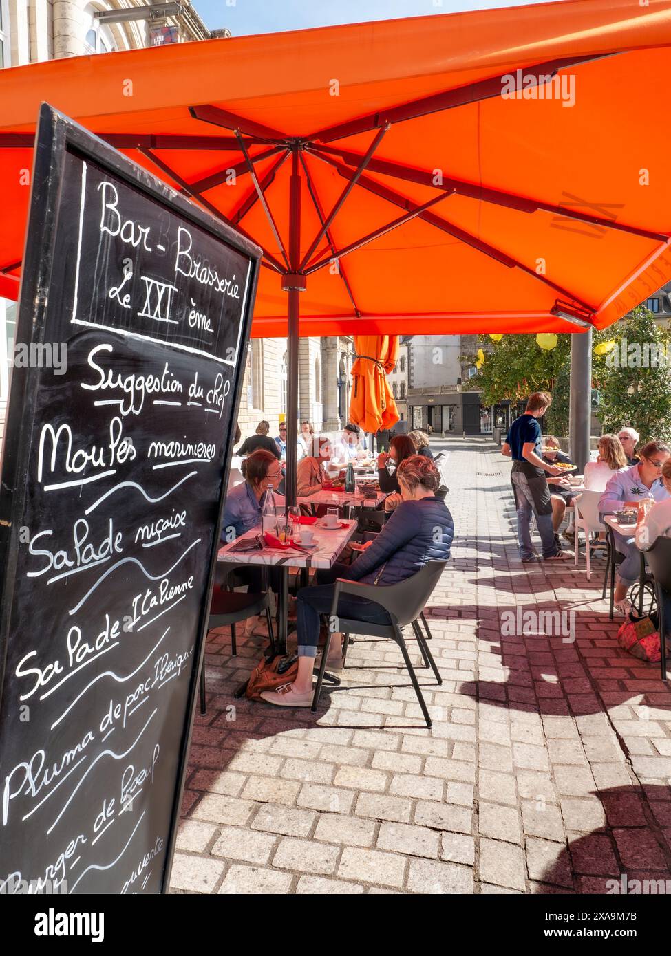 Brittany French Restaurant Blackboard Menu Alfresco Dining in Quimper presso il Sunny Terrace Restaurant «le XX1’eme» (il 21°) menù del giorno con specialità della Bretagna e cameriere che serve Quimper France Foto Stock