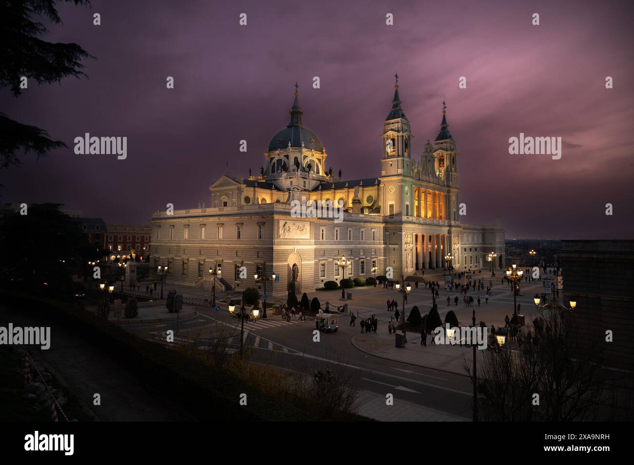 Una bellissima cattedrale illuminata di notte con gente intorno Foto Stock