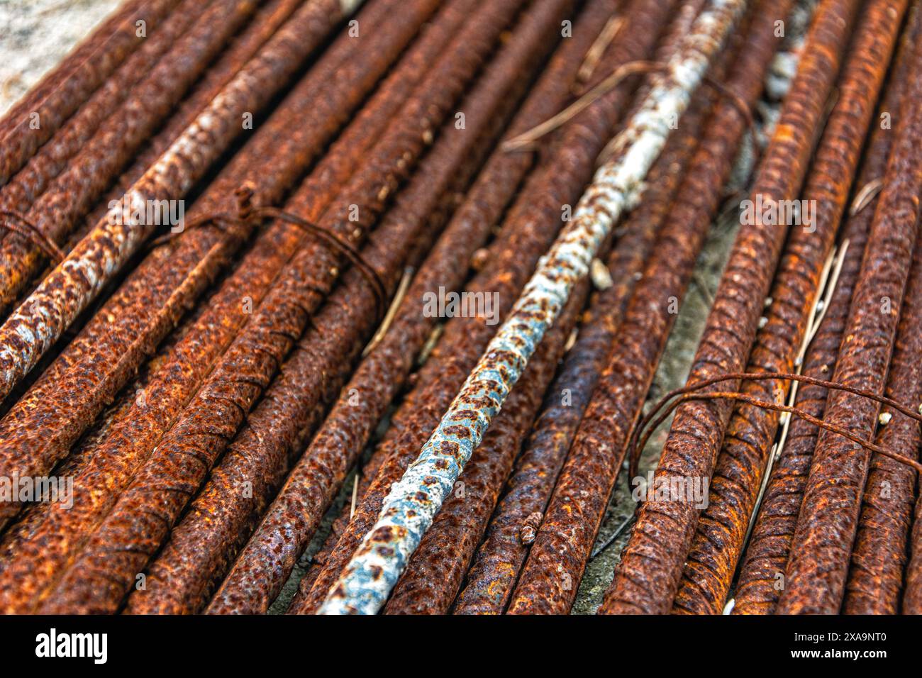 Molte barre di acciaio arrugginite sparse sul terreno o sulla recinzione Foto Stock