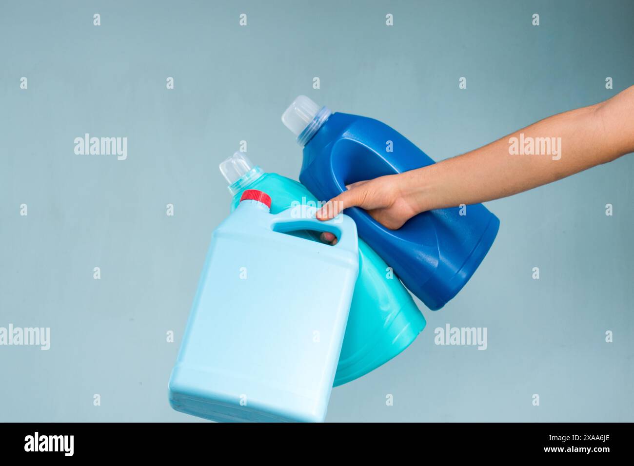 La mano tiene in mano i contenitori blu per il prodotto detergente Foto Stock