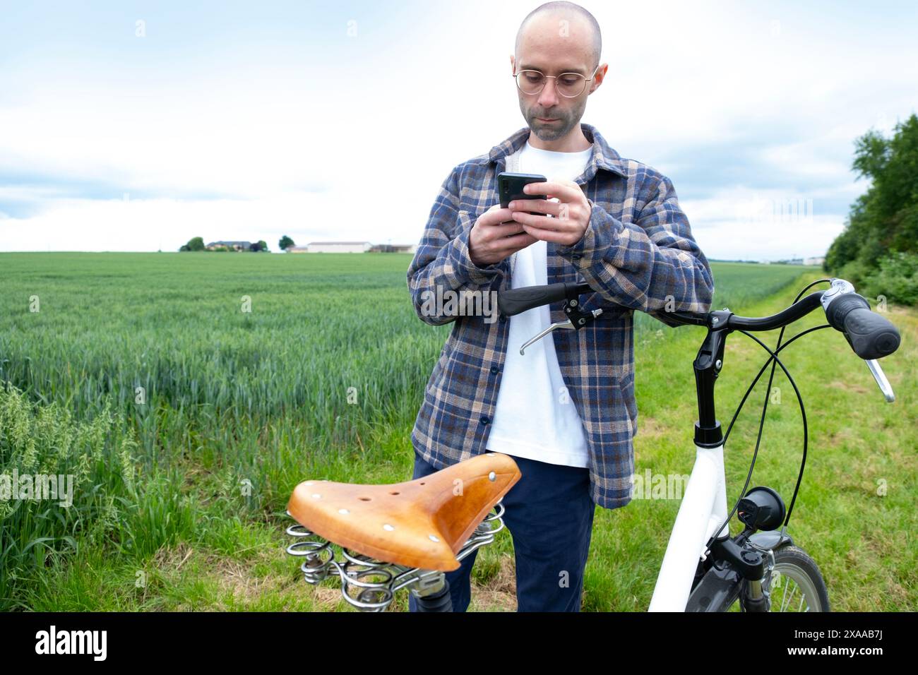 il tranquillo viaggio di un giovane ciclista attraverso campi verdeggianti, un'armoniosa miscela di trasporto eco-consapevole e serenità della natura Foto Stock