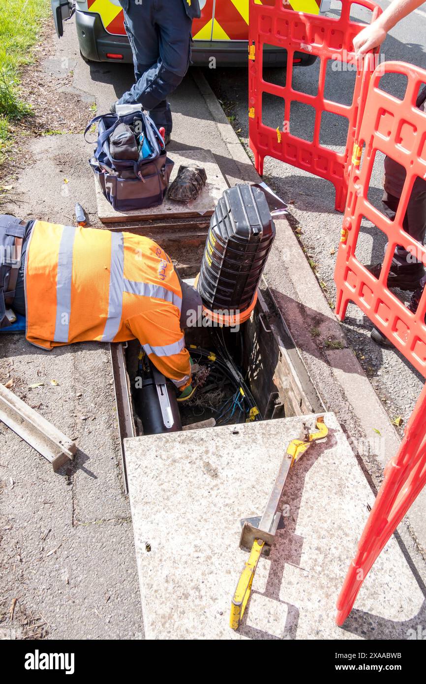 Ingegnere Openreach che lavora sul cablaggio in tombino, Church Lane, Cherry Willingham, Lincoln, Lincolnshire, Inghilterra, Regno Unito Foto Stock