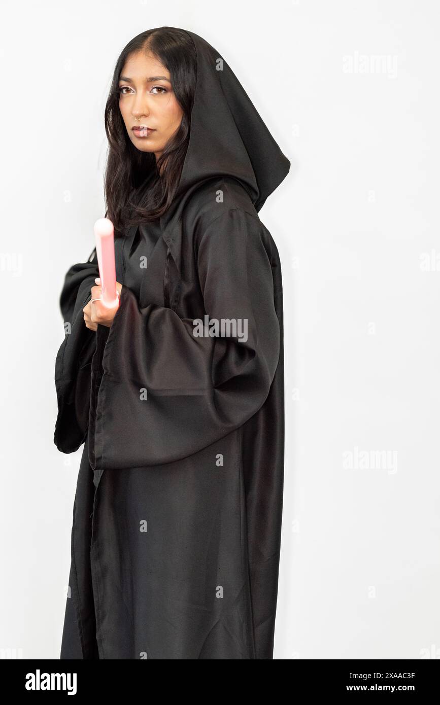 Una donna in vestaglia porta una spada leggera sullo sfondo di una parete bianca Foto Stock