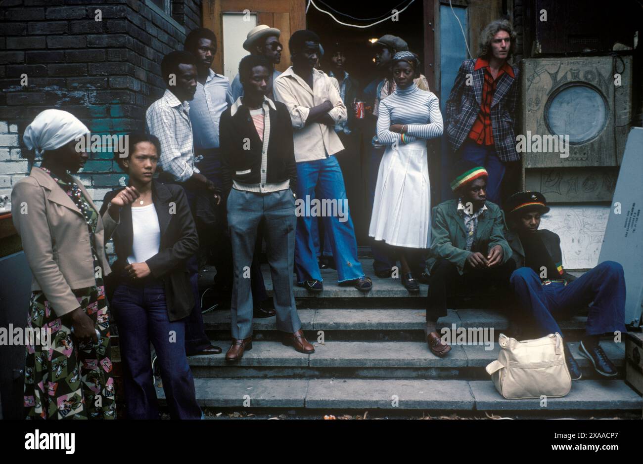Giovani adulti britannici neri al Carnevale di Notting Hill fuori da un edificio della comunità dove viene suonato il sistema audio reggae. Un uomo bianco, armonia razziale. Notting Hill, Londra, Inghilterra 27 agosto 1979. 1970 UK HOMER SYKES Foto Stock