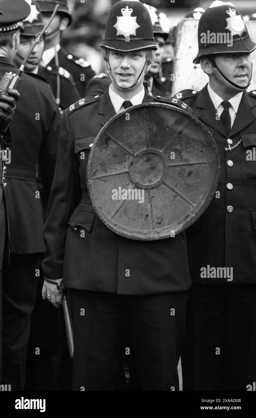 La rivolta del carnevale di Notting Hill agosto festivi lunedì 1976. La polizia usa i vecchi coperchi in gomma come scudo e tira i loro manichini. Notting Hill, Londra, Inghilterra 30 agosto. 1970 UK HOMER SYKES Foto Stock