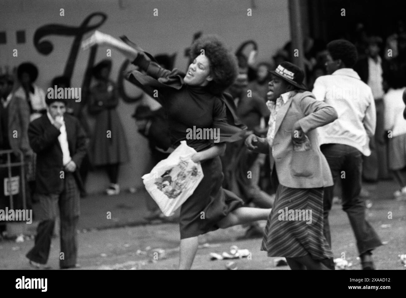 Tumulti di Carnevale di Notting Hill 1976. La polizia viene attaccata prevalentemente dalla comunità nera; una ragazzina lancia un missile nella linea di polizia. Notting Hill, Londra, Inghilterra 30 agosto. 1970 UK HOMER SYKES Foto Stock