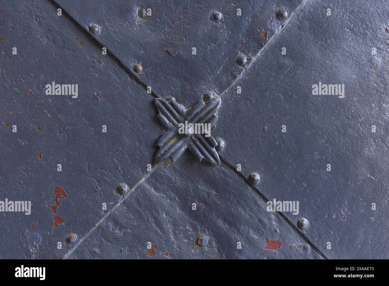 fotografia ravvicinata di un dettaglio di un cancello in metallo grigio dipinto medievale con rivetti e fiori decorativi Foto Stock