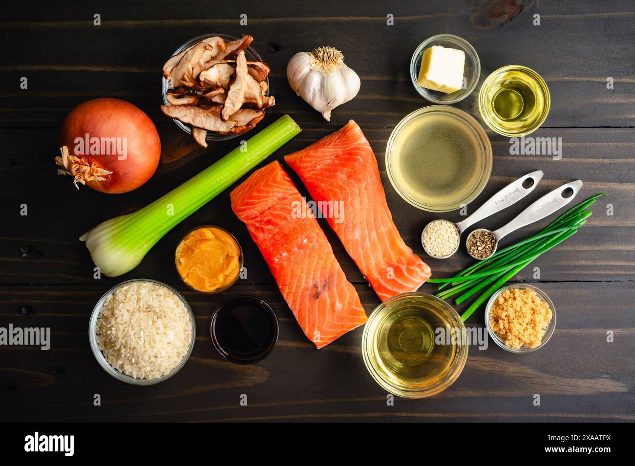 Salmone scottato con risotto ai funghi ingredienti: Filetti di pesce, riso arborio, vino bianco e altri ingredienti grezzi su un tavolo di legno Foto Stock