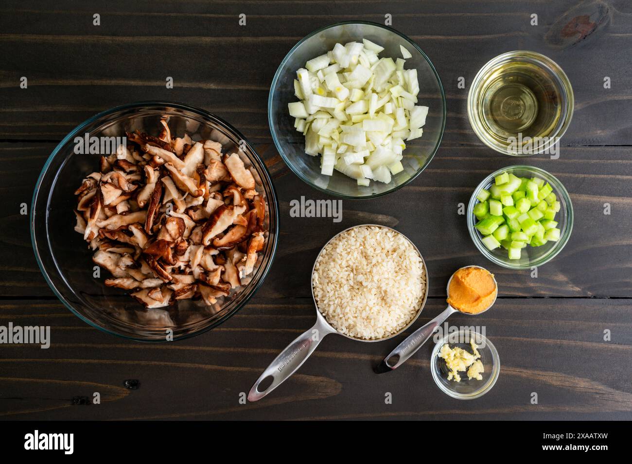 Risotto ai funghi su una tavola di legno: Riso arborio crudo con funghi shiitake crudi, cipolla e sedano a dadini, vino bianco e molto altro Foto Stock
