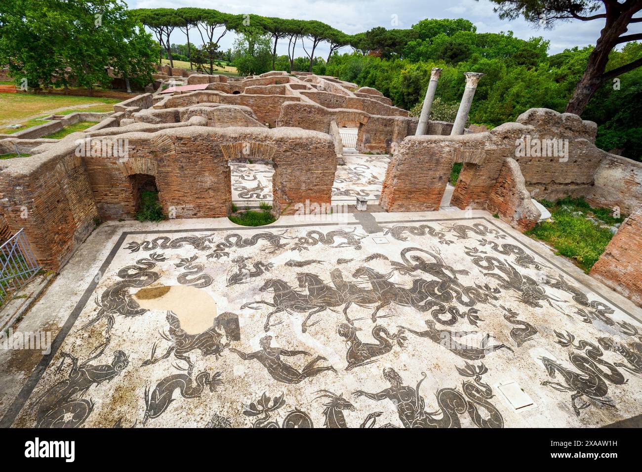 Mosaico raffigurante Nettuno con tridente, al volante di un carro a quattro cavalli trainato da cavallucci marini, circondato da delfini e tritoni che soffiano su conchiglie a cavallo e accompagnato da tritoni - Terme di Nettuno - collegati al Decumanus da un portico arroccato che ha monumentalizzato questo lato della strada, le terme risalgono alla fine del i secolo d.C. ma furono ricostruite dall'imperatore Adriano (117-138) e completate nel 139 d.C. dall'imperatore Antonino Pio.- Parco Archeologico di Ostia Antica, Roma, Italia Foto Stock