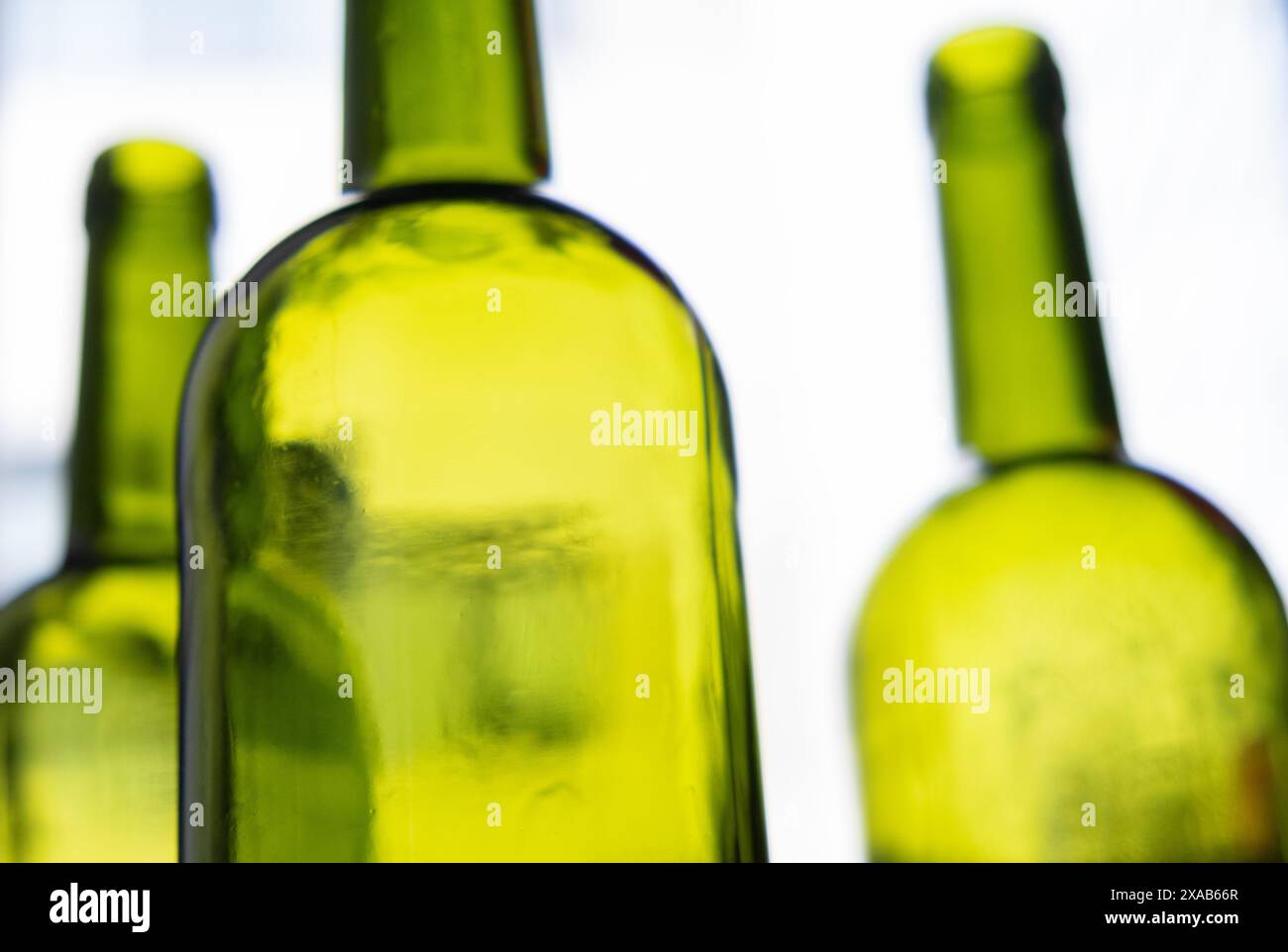 composizione con bottiglie verdi di vino rosso su sfondo chiaro neutro Foto Stock
