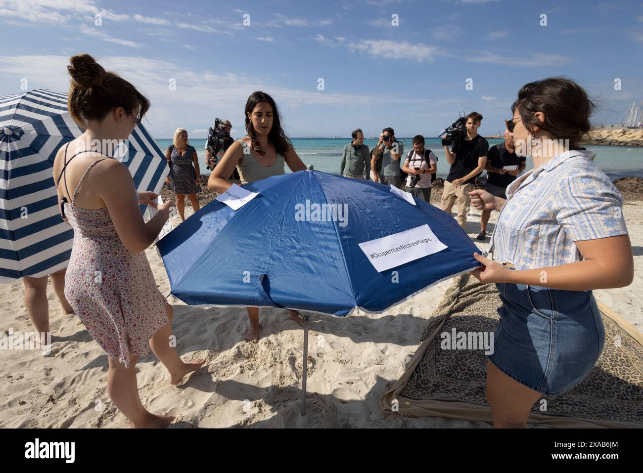 I manifestanti spagnoli alla spiaggia di sa Rapita simulano uno scenario di spiaggia ricco per enfatizzare il sovraffollamento delle spiagge dovuto al turismo eccessivo a Maiorca. Foto Stock