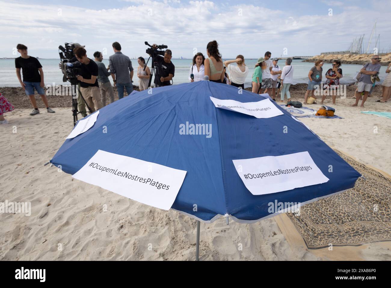 I manifestanti spagnoli alla spiaggia di sa Rapita simulano uno scenario di spiaggia ricco per enfatizzare il sovraffollamento delle spiagge dovuto al turismo eccessivo a Maiorca. Foto Stock