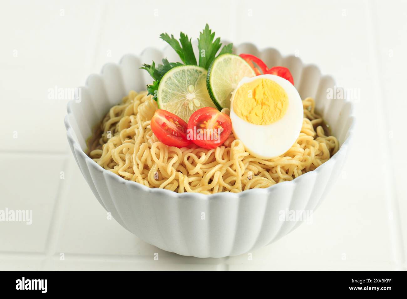 Indomie Rebus o Instant Boiled Noodle con Soto Flavour, Instant Noodle indonesiane con uovo bollito, pomodoro e lime affettato Foto Stock