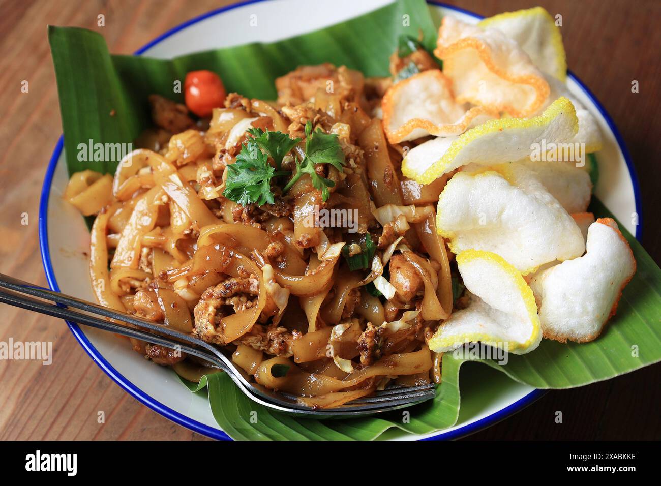 Primo piano Char Kway Teow o Kwetiau, tagliatelle piatte di riso cinesi. Servito con Kerupuk o Crackers Foto Stock