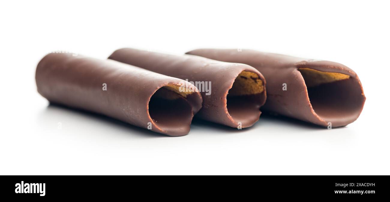 Rotoli di cialde ricoperti di cioccolato impilati uno sopra l'altro su uno sfondo bianco. I rotoli sono di colore marrone chiaro e ricoperti da un sottile strato di Foto Stock