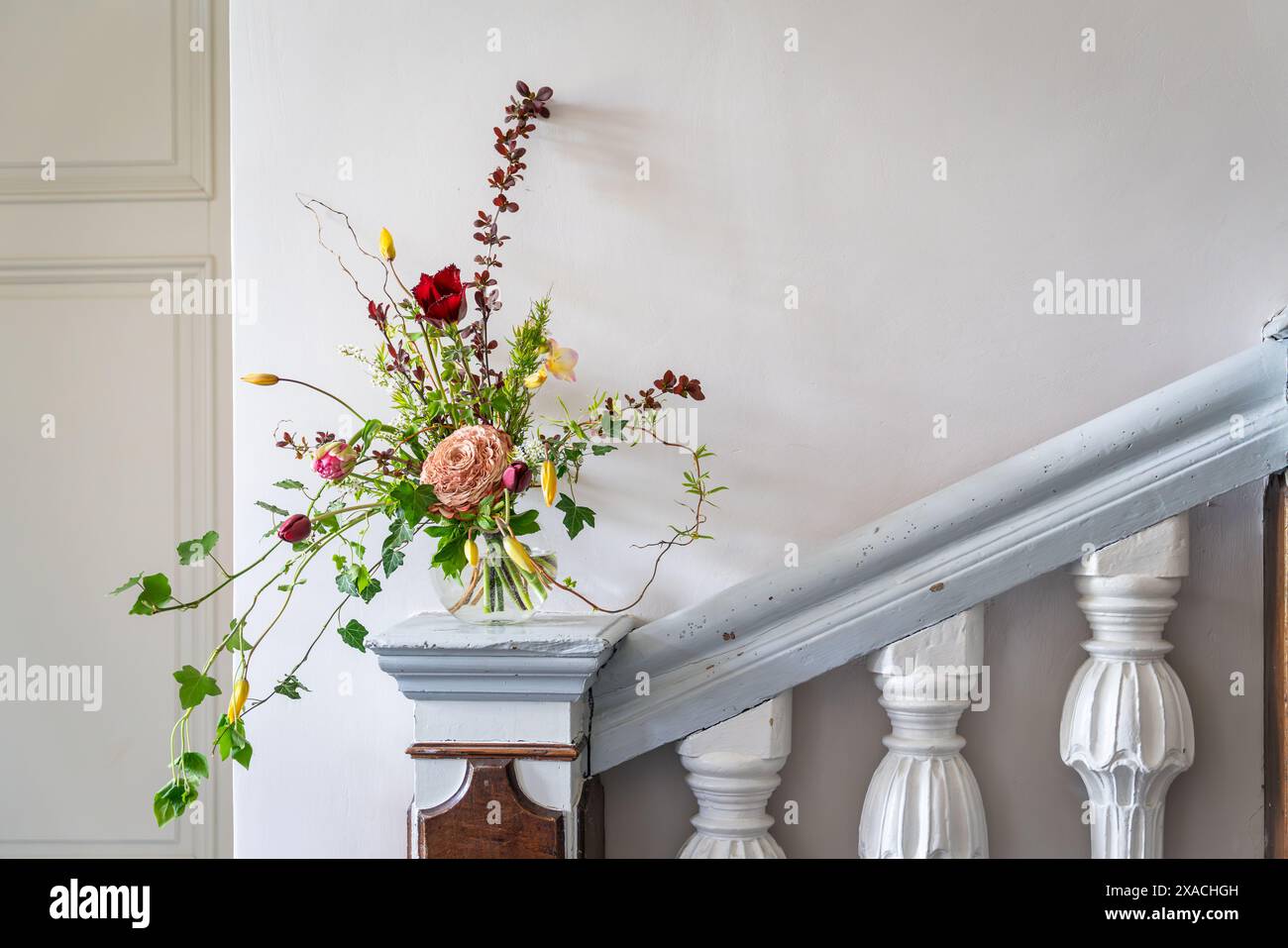 Design degli interni con bouquet di fiori primaverili e glamelia in vaso su colonna in legno. Primavera Foto Stock