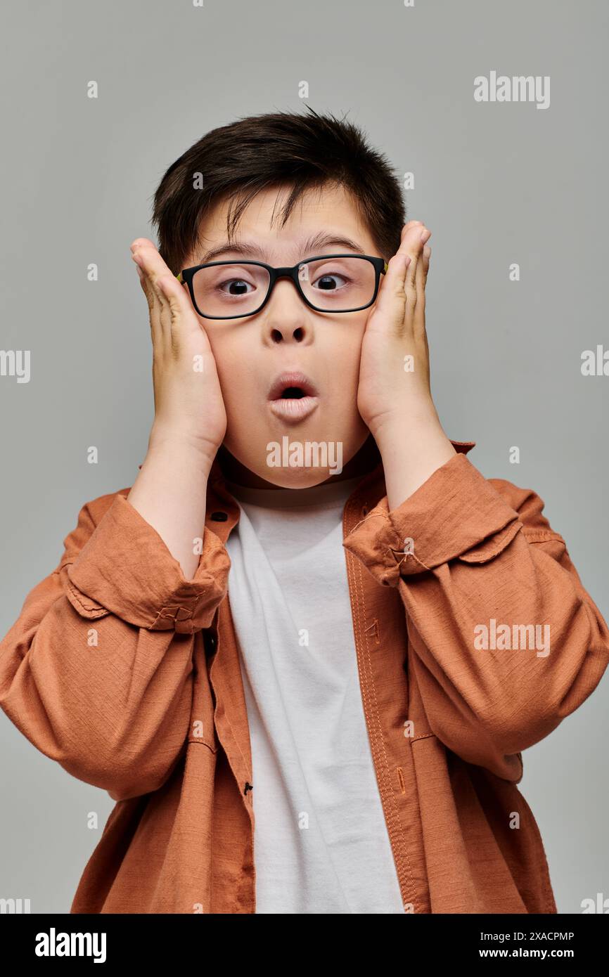 Bambino con sindrome di Down con occhiali che guardano la macchina fotografica. Foto Stock