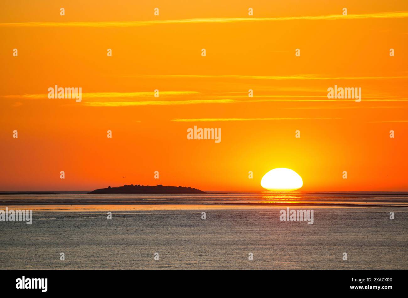 Pittoresco, dorato, magnificamente bellissimo tramonto sul mare, isola Langluetjen II lontana, sole a forma di uovo all'orizzonte, arancio che brilla Foto Stock