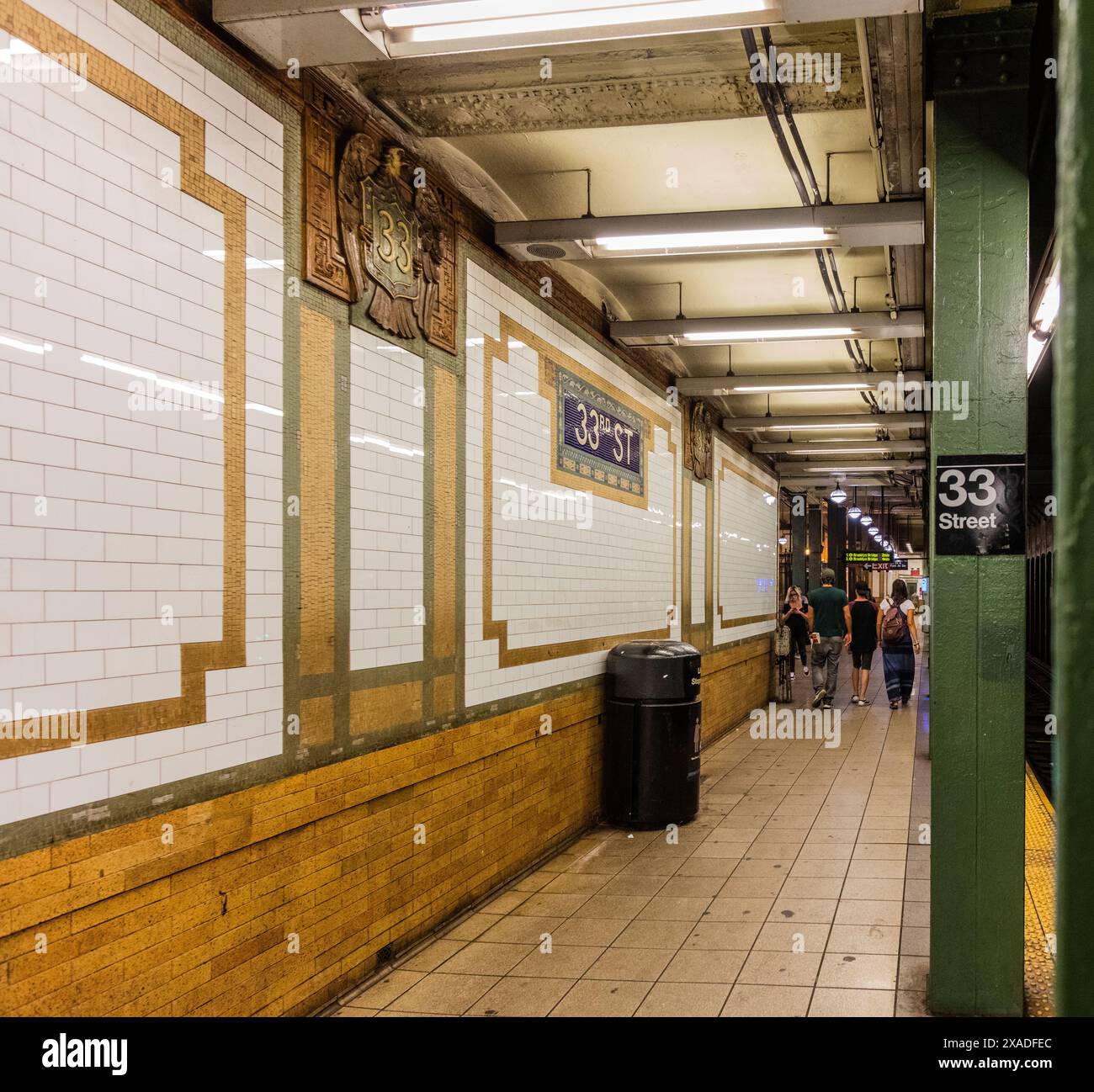 New York City, Stati Uniti - 23 agosto 2017: Nella 33rd Street station della metropolitana di New York City, con targhe di faience (1904) e persone. Foto Stock