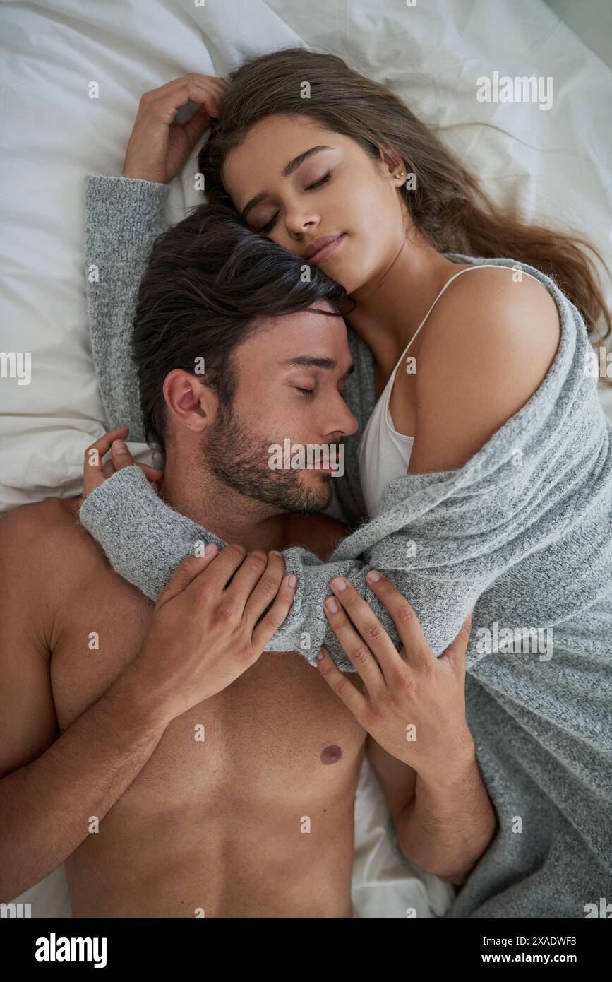 Coppia, coccole e sonno abbracciati nel letto per romanticismo mattutino, amore e legame nel fine settimana. Relazione, uomo e donna che si sono messi insieme in casa per Foto Stock