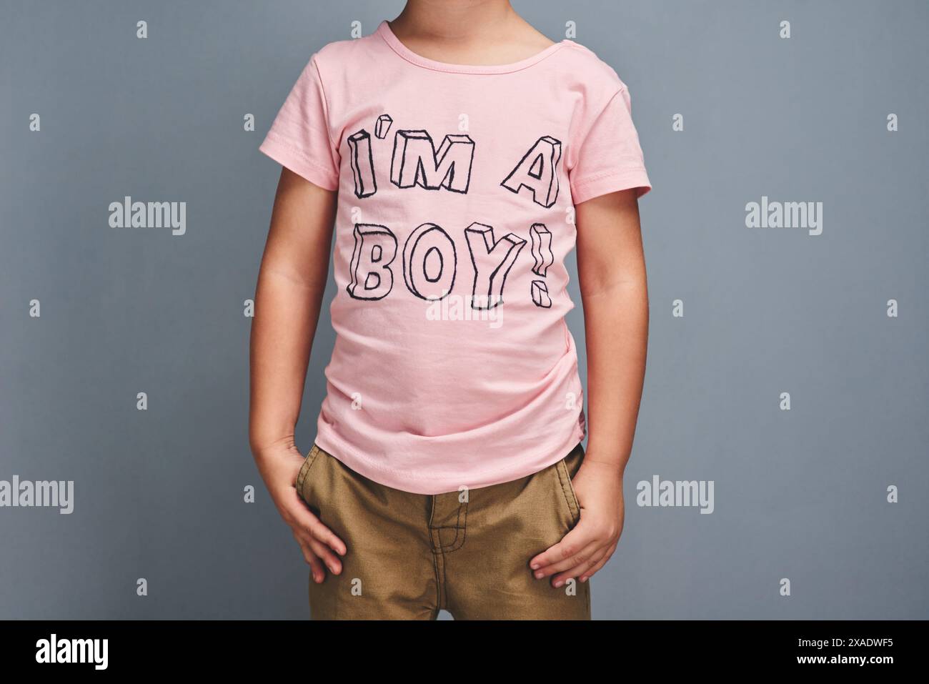 Ragazzo, affermazione e stampa su camicia per l'identità di genere, lo stile e la moda audace su sfondo grigio. Bambino, bambino e bambino con abiti rosa per Foto Stock