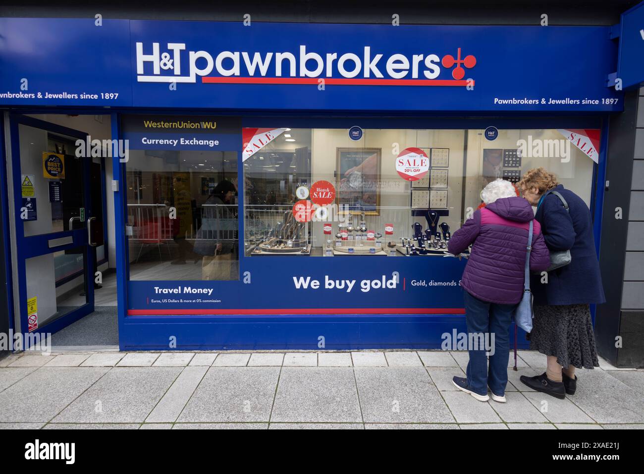 Una coppia di donne anziane che guardano gioielli nella vetrina H&T Pawnbrokers di Basingstoke, Hampshire, Regno Unito Foto Stock