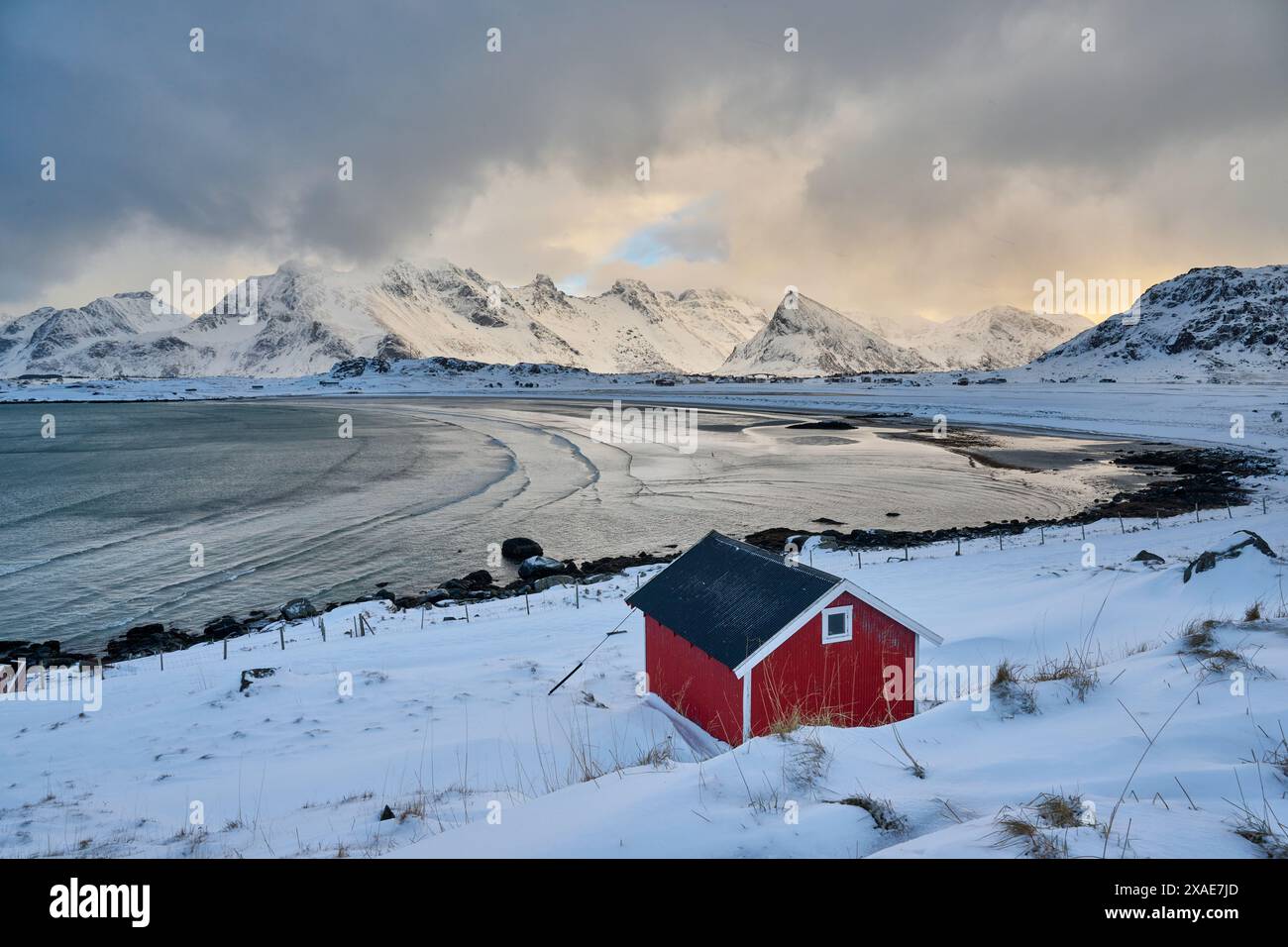 Capanna rossa nel paesaggio invernale con mare e montagne a Sandbotnen, Lofoten, Norvegia, Europa Foto Stock