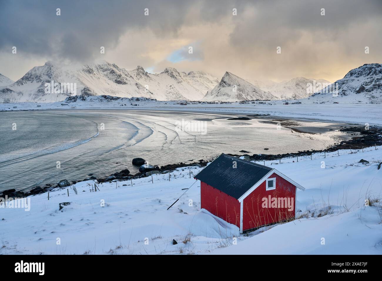Capanna rossa nel paesaggio invernale con mare e montagne a Sandbotnen, Lofoten, Norvegia, Europa Foto Stock
