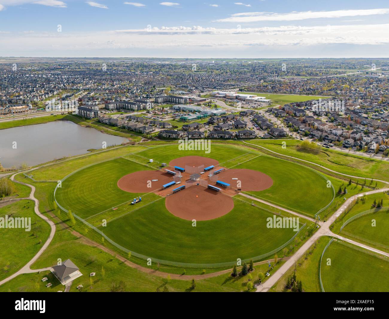 Diamanti aerei da baseball che si affacciano sui parchi della città con condomini e un lontano laghetto di acqua piovana ad Airdrie, Alberta Canada. Foto Stock