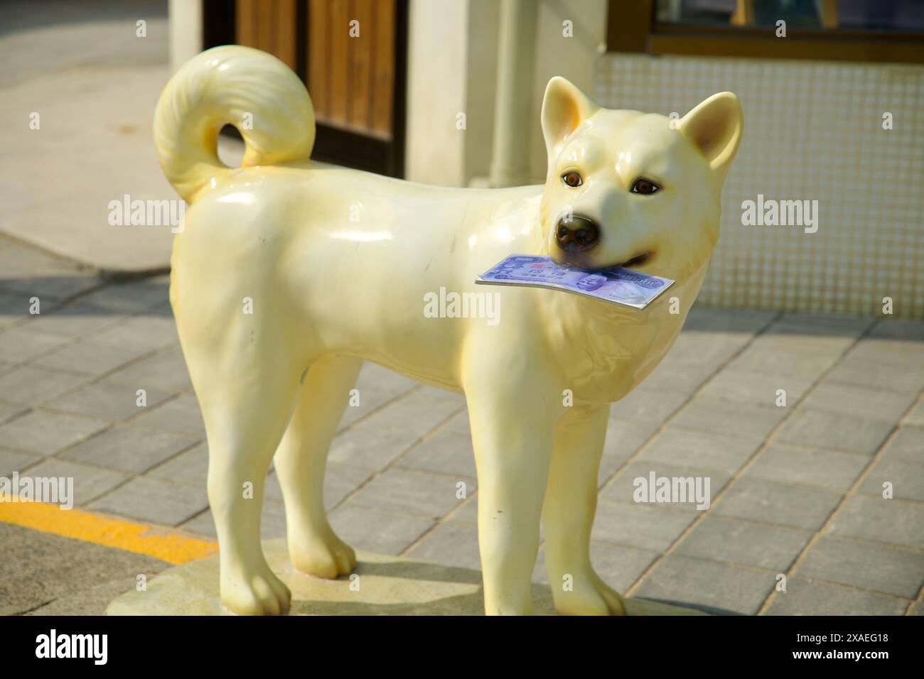 Ulsan, Corea del Sud - 17 marzo 2024: Una stravagante scultura di un cane che tiene soldi in bocca al villaggio culturale delle balene di Jangsaengpo. Questa divertente deta Foto Stock