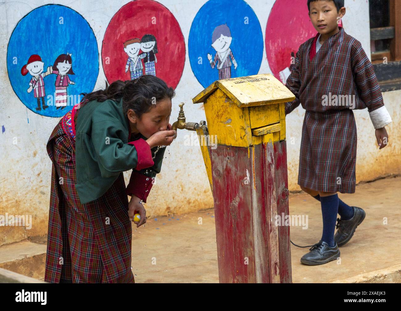 Ragazza bhutanese che beve acqua di rubinetto alla Rubesa Primary School, Wangdue Phodrang, Rubesagewog, Bhutan Foto Stock