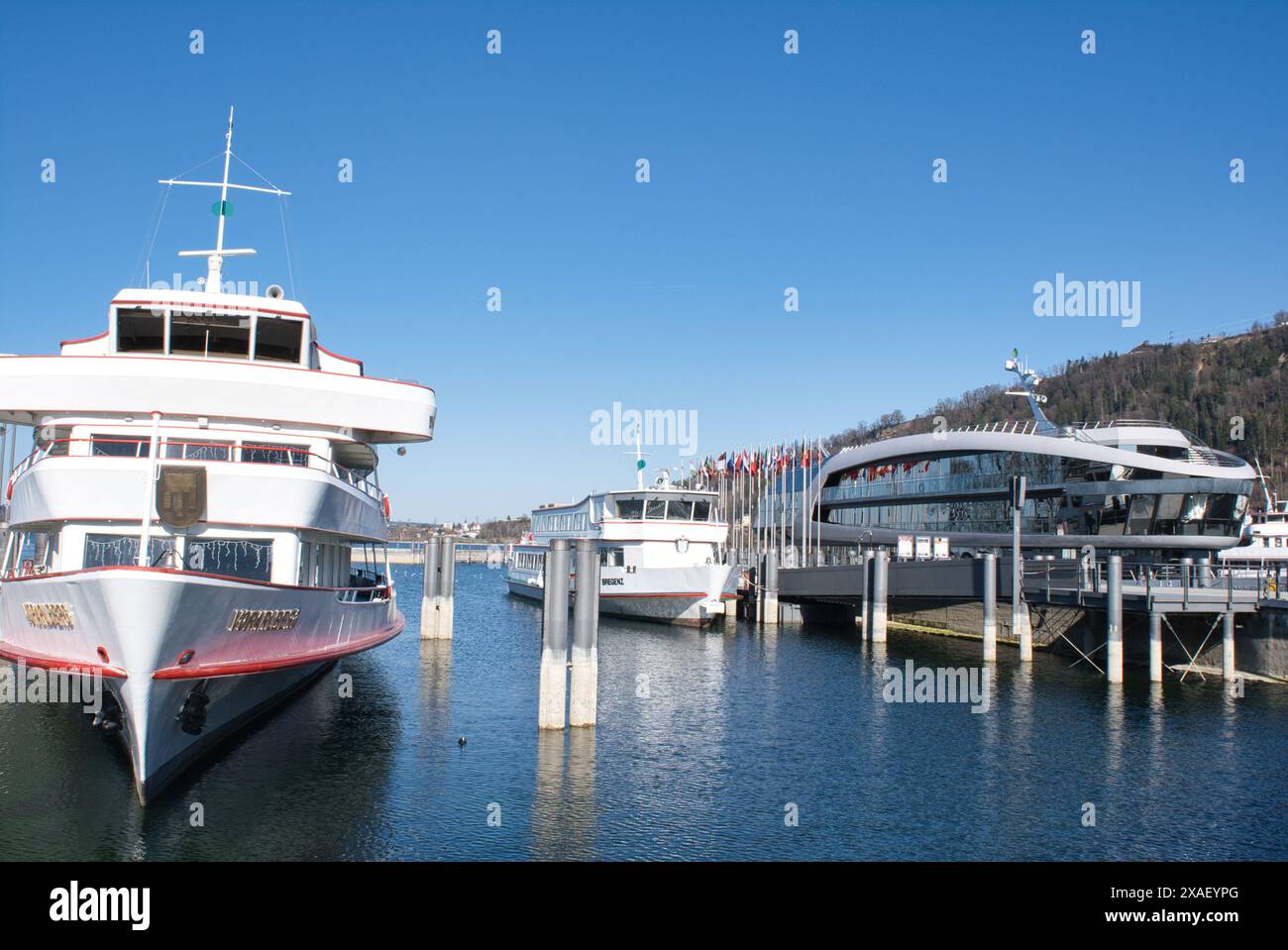 Una grande barca bianca è ormeggiata accanto a una barca più piccola. L'acqua è calma e il cielo è limpido Foto Stock