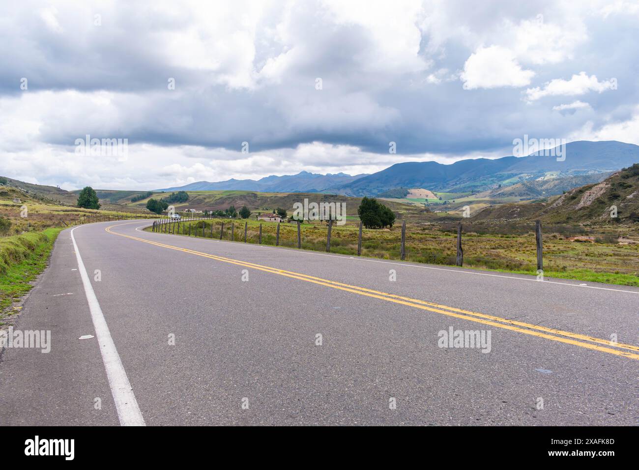 paesaggio montuoso con una strada che scompare all'orizzonte in un clima freddo e verdi pascoli laterali Foto Stock