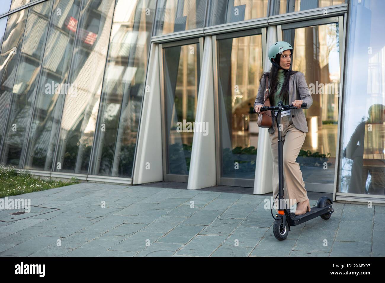 una donna d'affari professionale nel settore del copyspace si vede elegantemente guidare il suo scooter elettrico mentre si sposta dall'ufficio a casa, Foto Stock