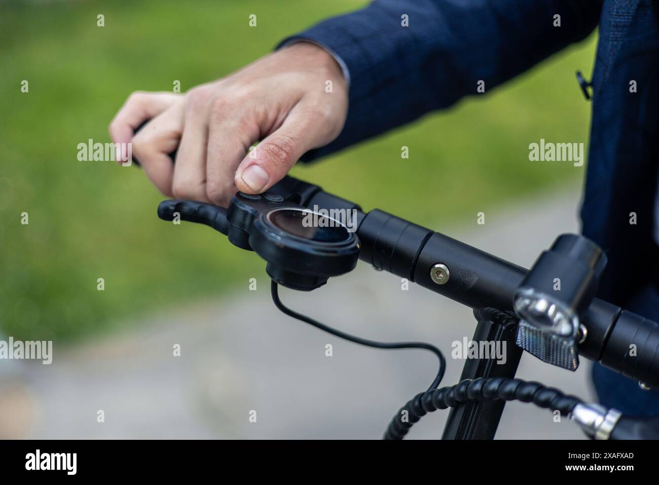 la mano ravvicinata di un uomo d'affari afferra saldamente il manubrio di uno scooter elettrico, simboleggiando il suo approccio eco-consapevole al passaggio al lavoro, scegliendo Foto Stock