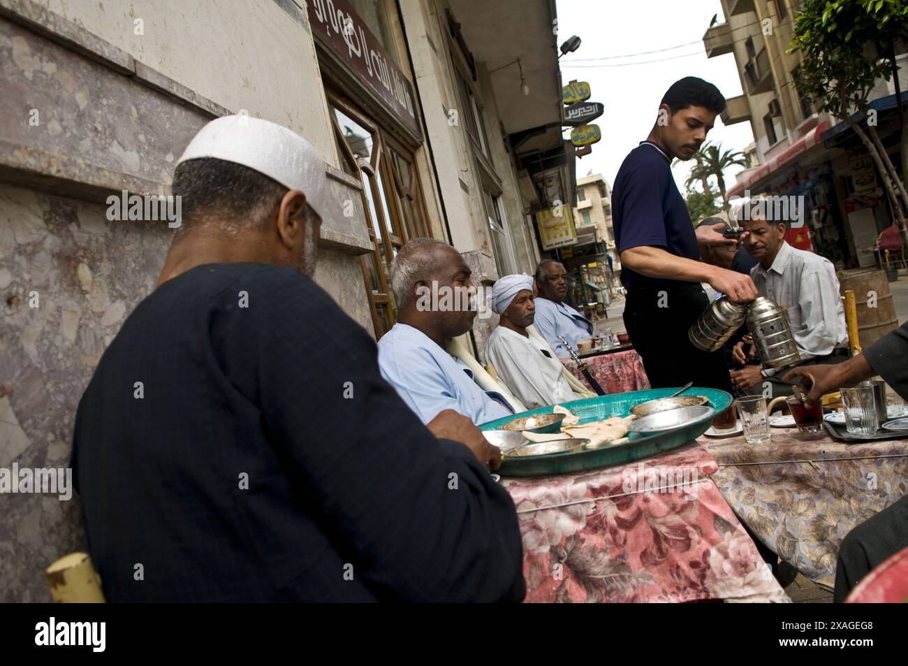 Uomini egiziani che gusteranno la colazione egiziana in un piccolo ristorante di strada ad Alessandria, in Egitto. Foto Stock