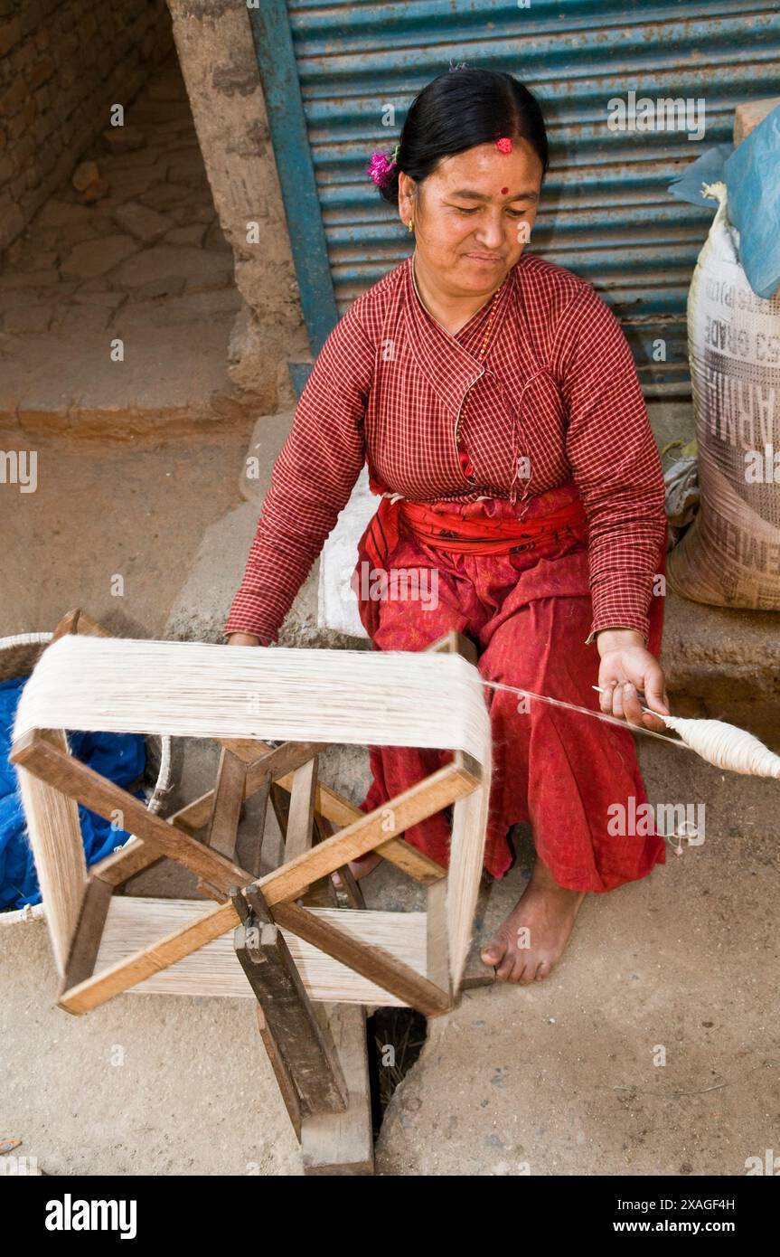 Una donna nepalese gira filo di lana con una ruota girevole a manovella a Patan, Kathmandu Valley, Nepal. Foto Stock