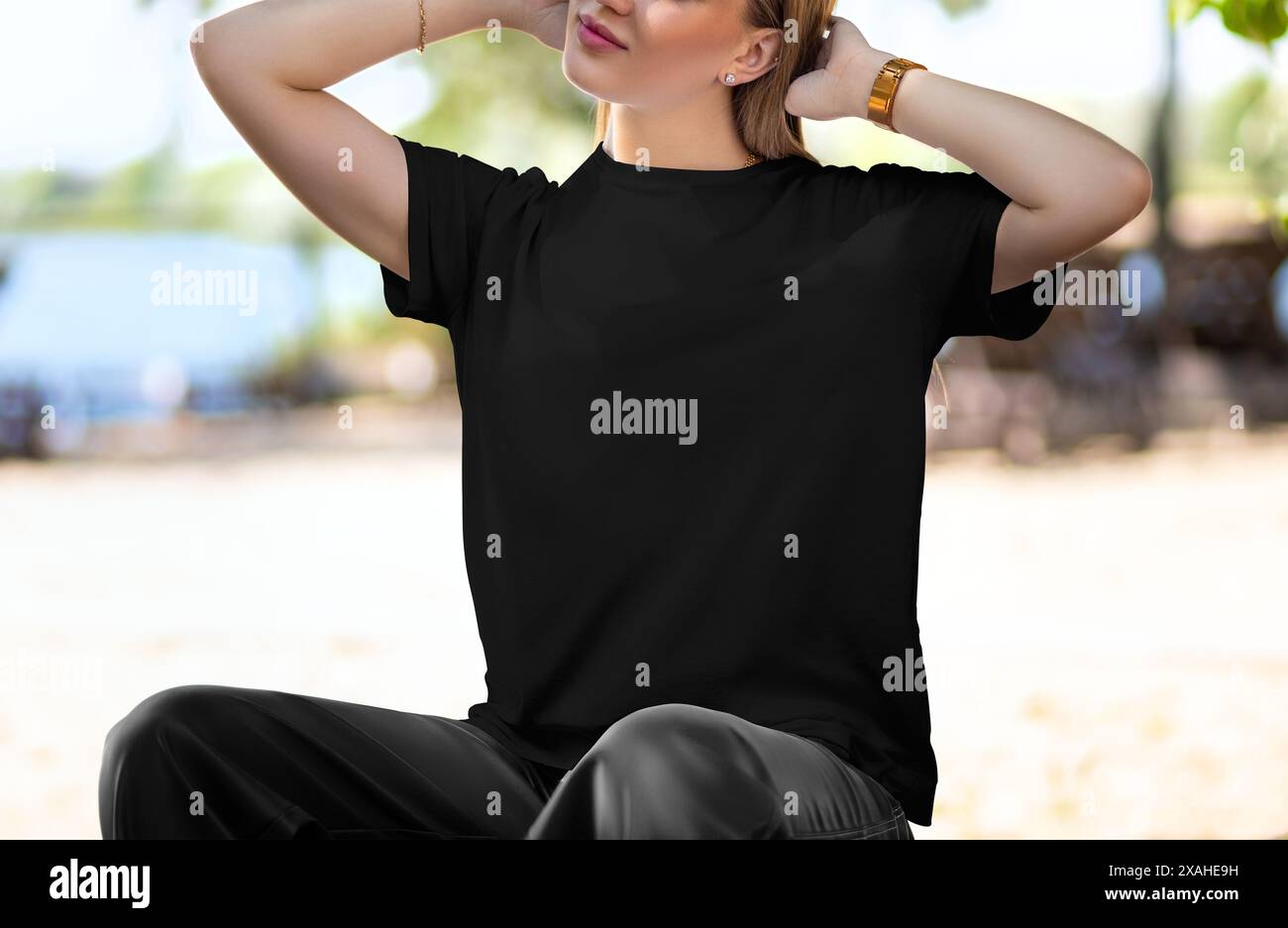 Modello di T-shirt nero su una ragazza bionda con sfondo naturale, vista frontale della camicia estiva, per design, branding, pubblicità. Texture casual Foto Stock